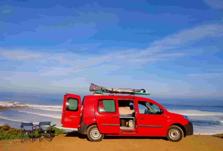 Red campervan parked by the coast in the Algarve, Portugal