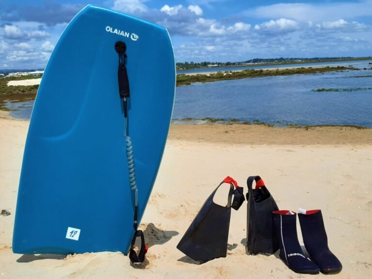 Blue bodyboard with fins on the beach in Faro, Algarve