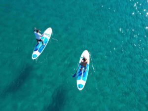Two people paddleboarding on clear turquoise water in the Algarve, Portugal
