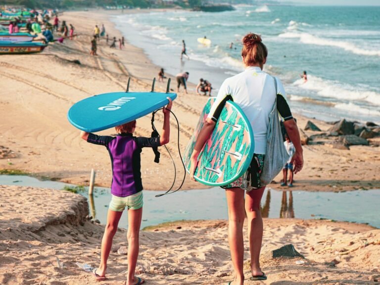 Parent and child carrying bodyboards and a surfboard on the beach