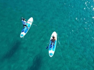 Two people paddleboarding on clear turquoise water in the Algarve, Portugal