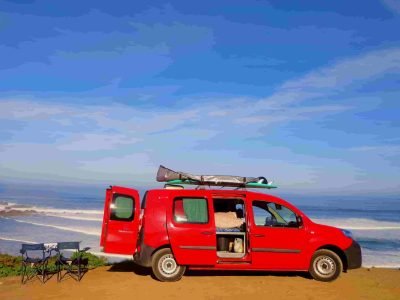 Red campervan parked by the coast in the Algarve, Portugal